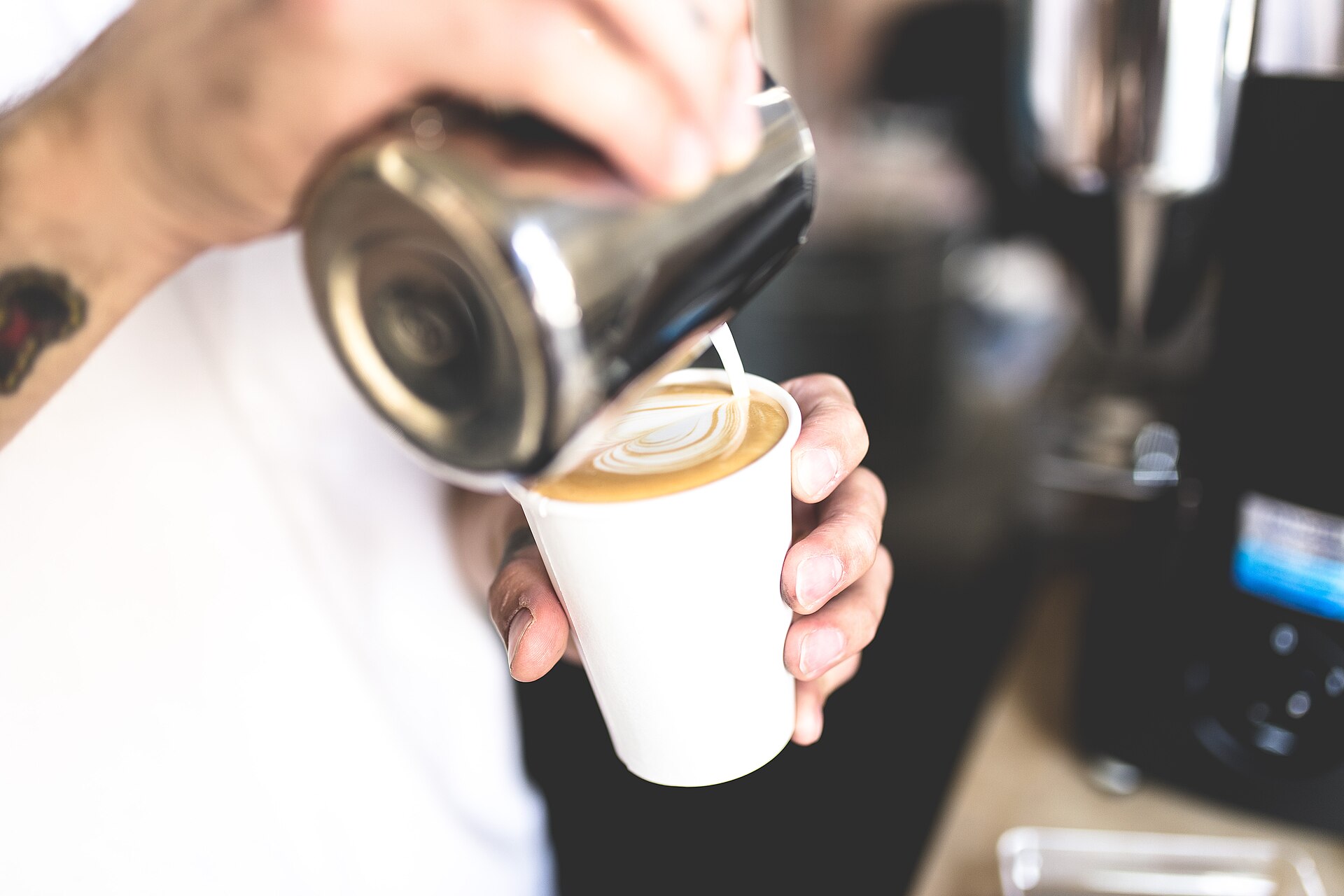 Milk being poured into a takeaway cup, drawing latte art.