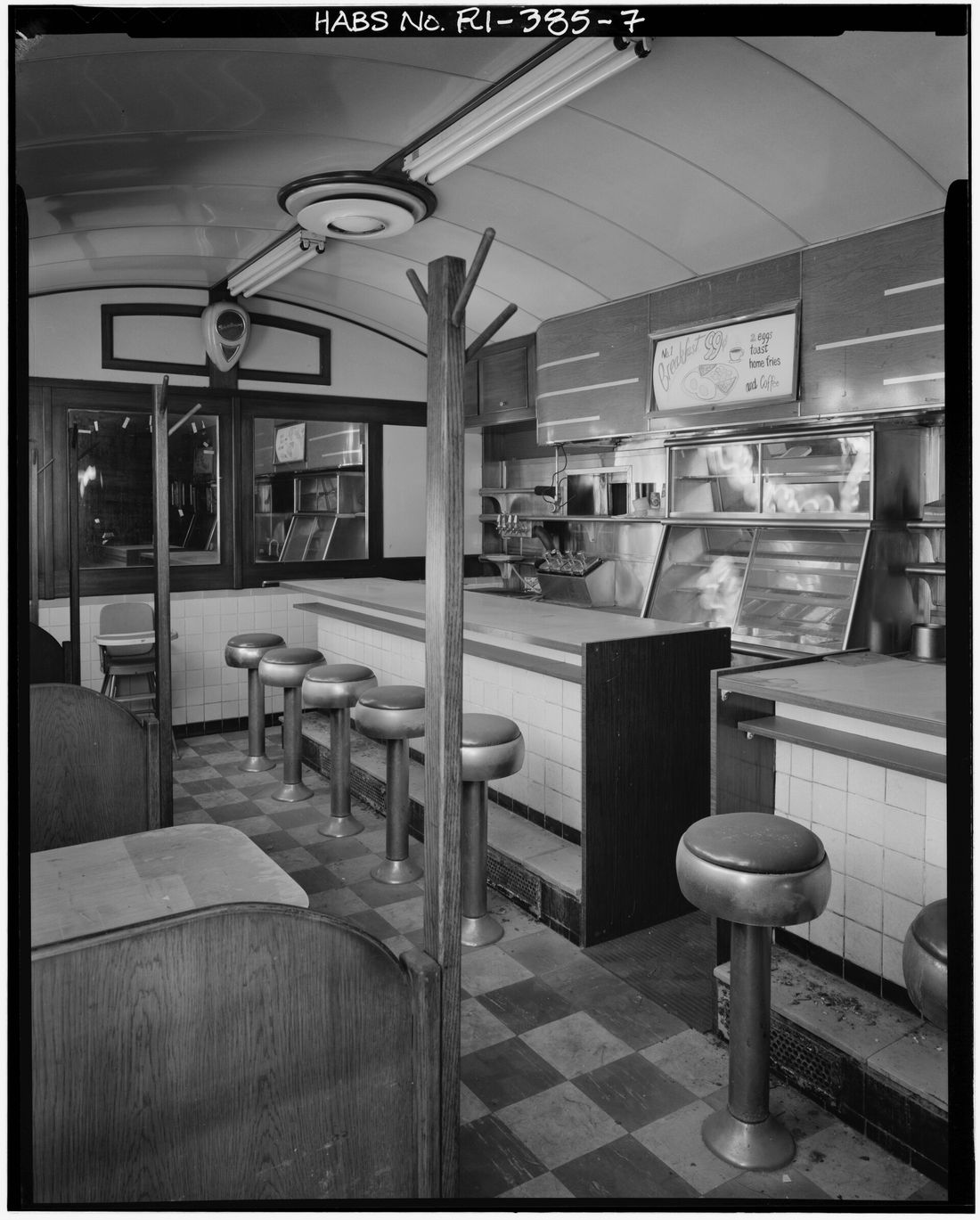 Stools along the counter of an empty diner, seen as if through a camera lens.